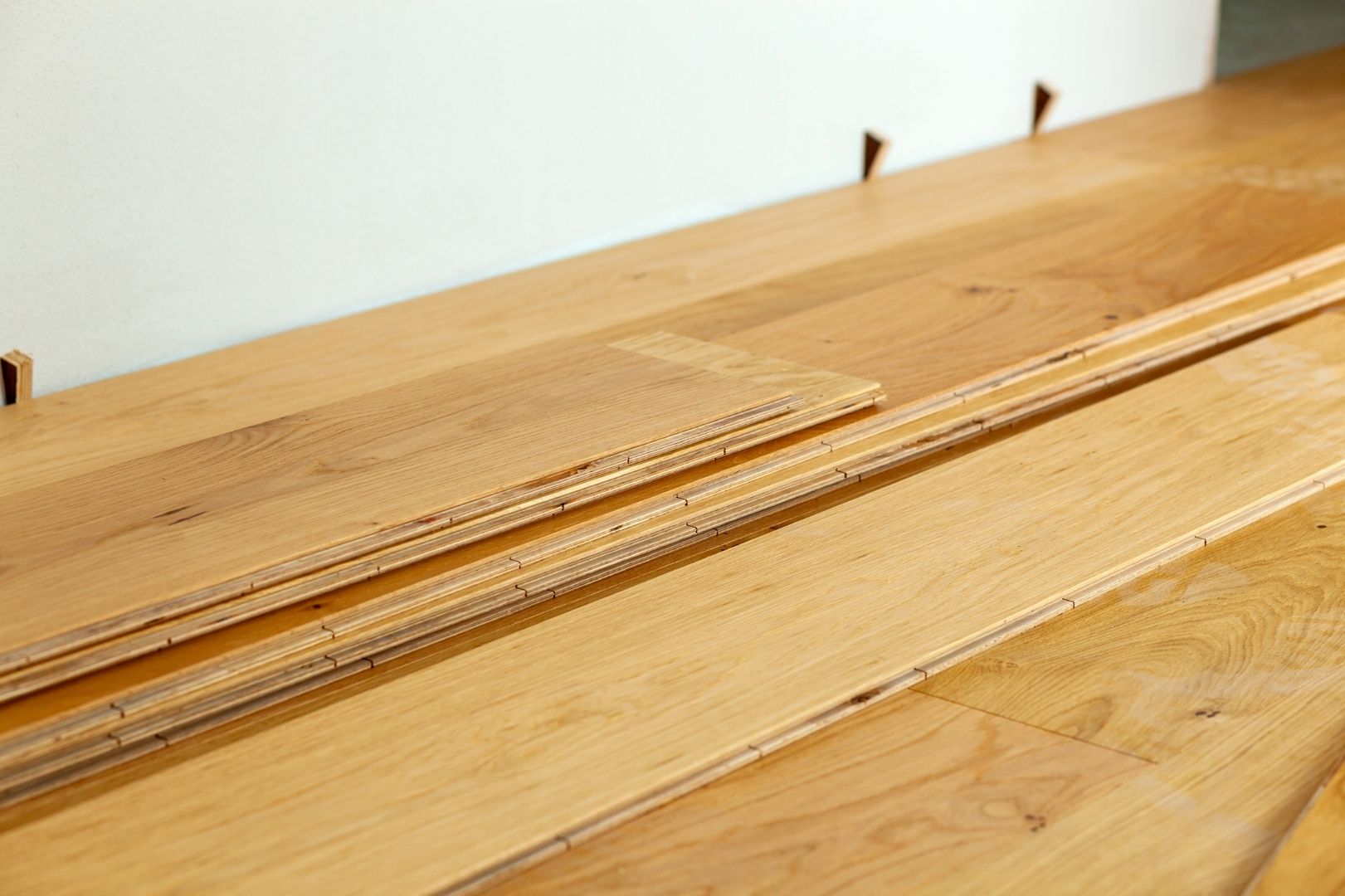 Lames de parquet en chêne massif brut entreposées pour une pose traditionnelle sur solives.