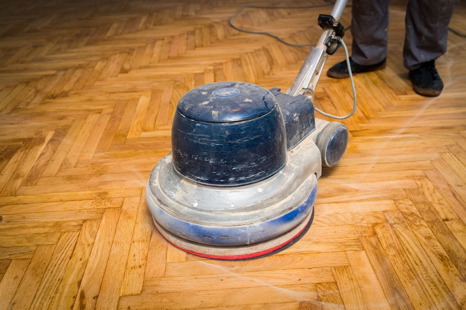 Ponçage d'un parquet ancien en chêne avec une ponceuse à parquet professionnelle circulaire.