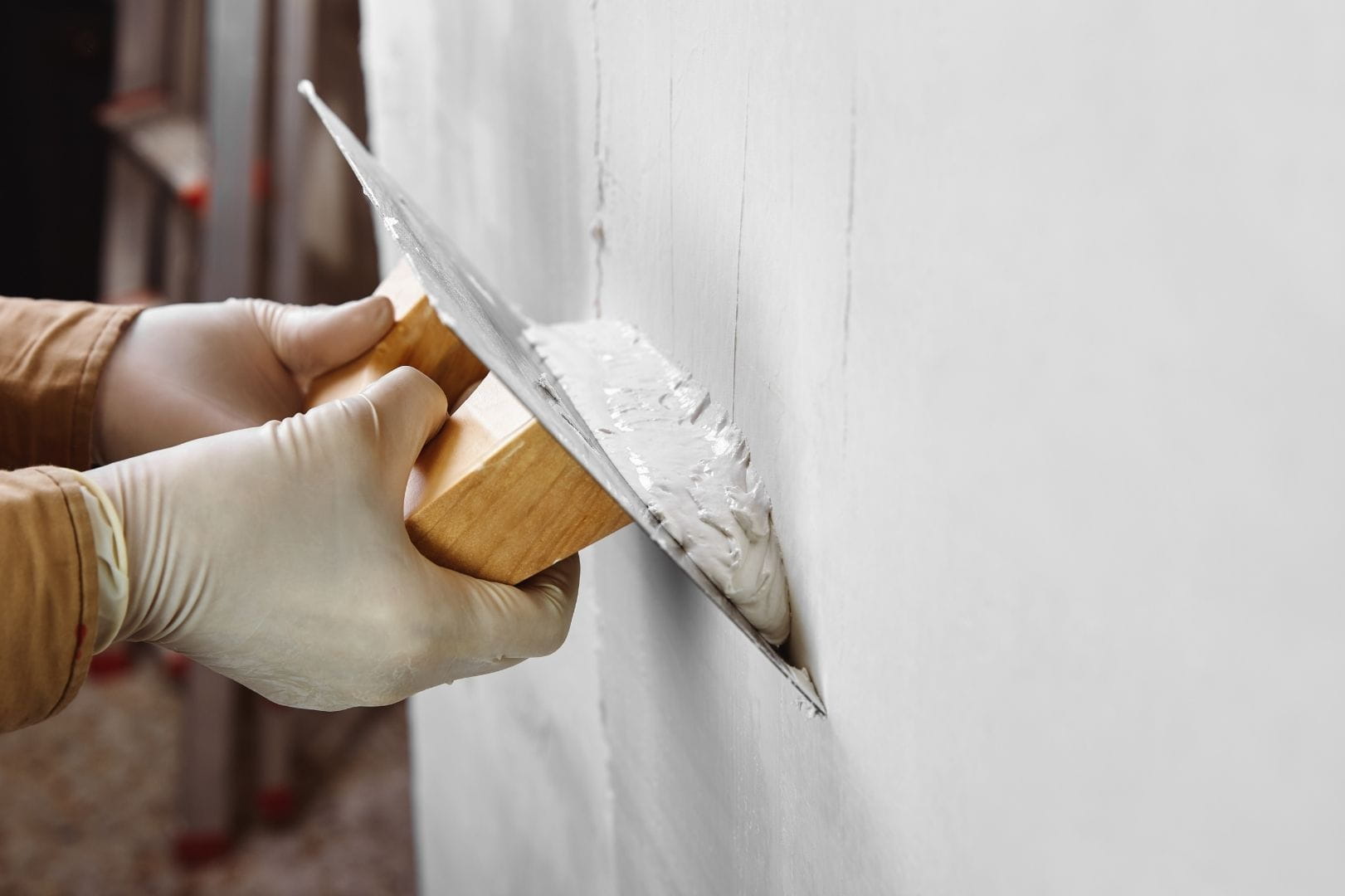 Artisan façadier appliquant un enduit de lissage à la taloche sur un mur extérieur en Eure-et-Loir (28).