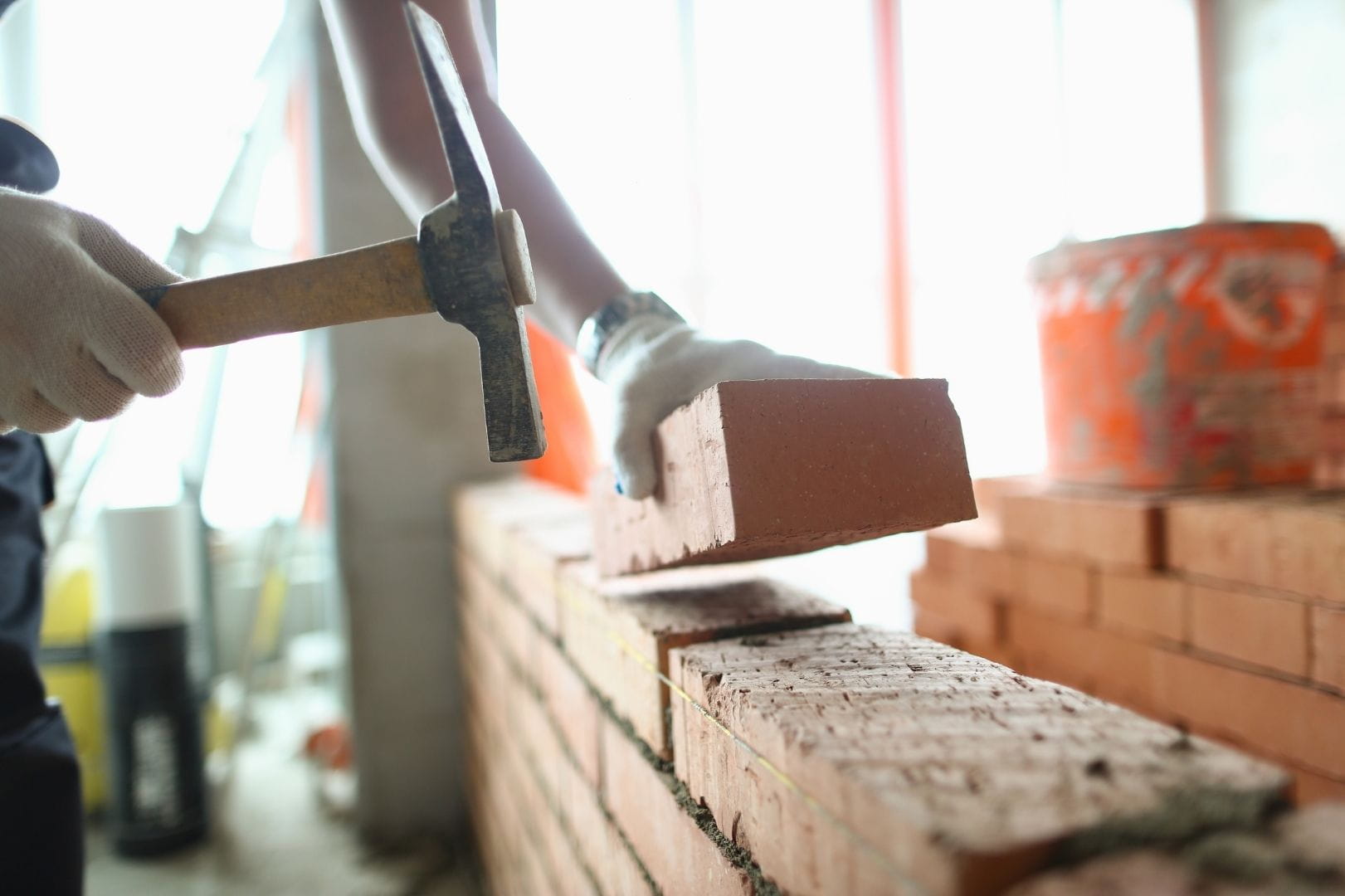 Artisan maçon posant des briques rouges avec précision sur un chantier de construction à Vernouillet.